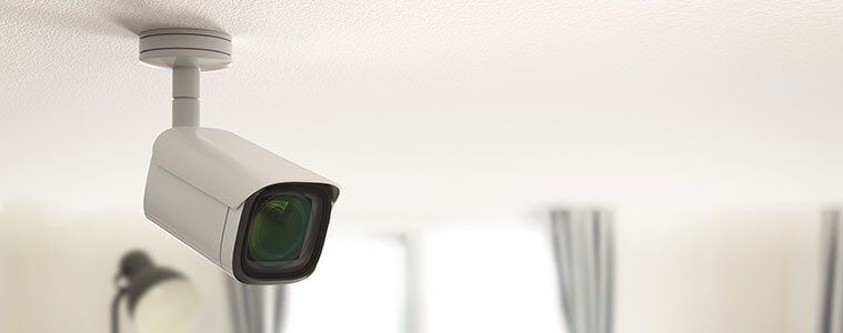 A security camera positioned on the ceiling of a living room in a house