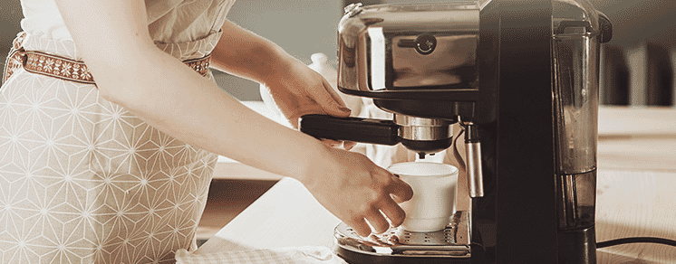 A lady making a coffee in her manual coffee machine 