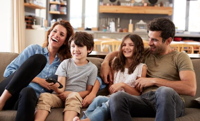 A family sit on the couch and watch TV together