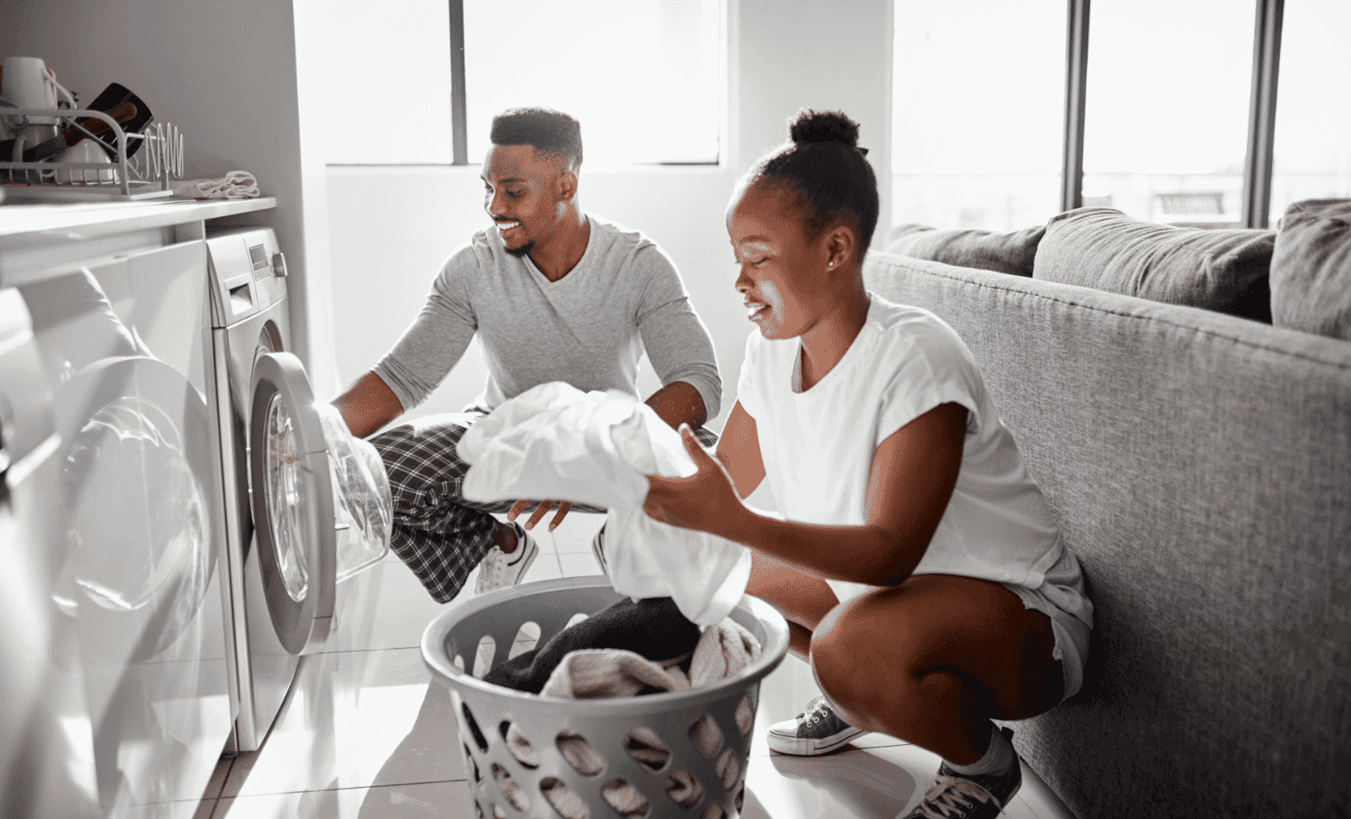 A young man and woman sort clothes together as they take them from the dryer
