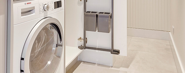 Detail of washing machine dryer and tall cupboard with builtin internal storage racks attached to the inside of the cupboard door