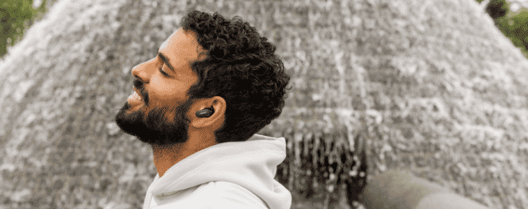 Man wearing his Bose QuietComfort Earbuds II whilst standing near a waterfall