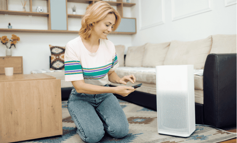A woman adjusts the settings on her air purifier through an app on her smart phone