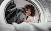 Smiling Woman loading clothes into her new clothes dryer