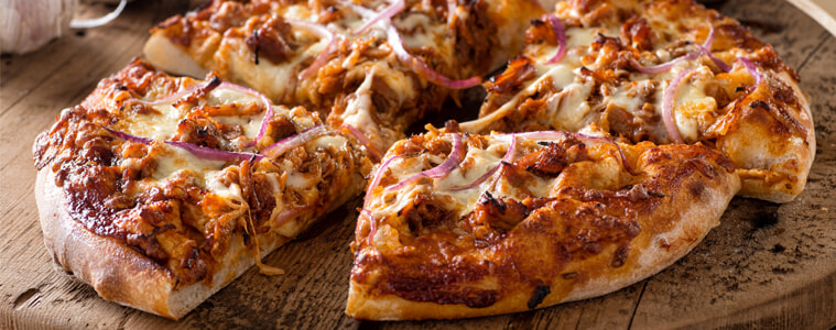 Spicy barbecue pulled pork pizza sliced on a wooden board and ready to eat