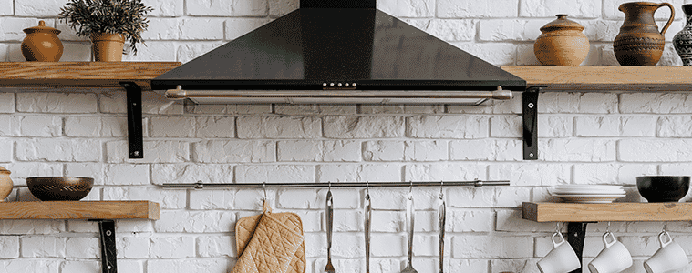 A stainless steel rangehood in a slick kitchen with copper pendant lights and dark wood cabinetry