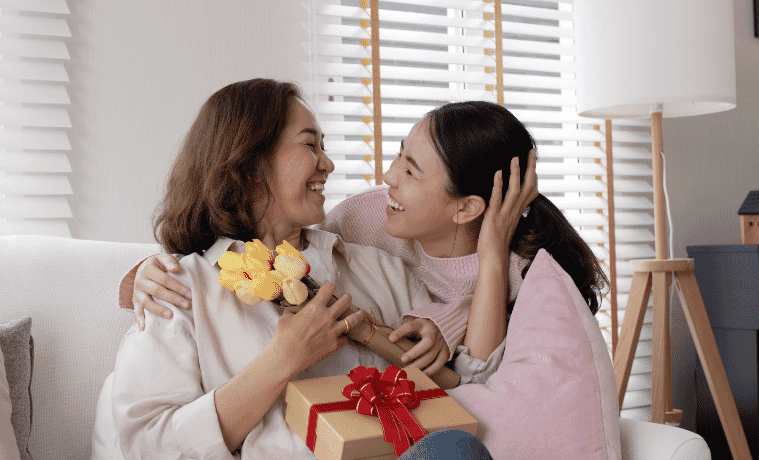 a daughter giving her mum a mothers day gift 