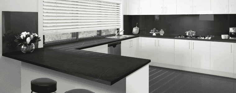 A white flat pack kitchen with black countertops and spalshback