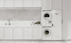A stacked washer and dryer in a large white laundry