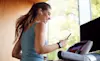 Woman smiling whilst using a treadmill and her smartphone
