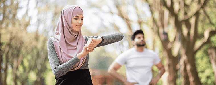 A woman checks her fitness tracker on a run while she takes a break with her running partner