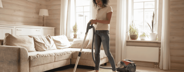 Woman cleaning her living room happily with her corded upright vacuum 