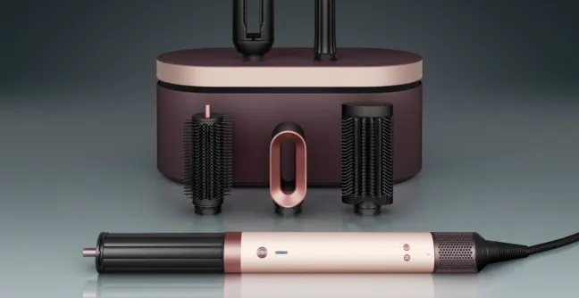Woman using Dyson Airwrap in silver and gold to curl her hair