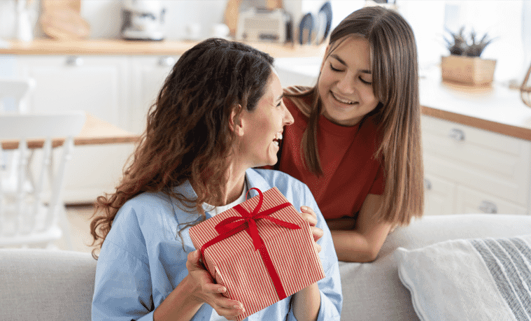 Mum receiving gift from daughter at home in the living room 