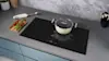 A Smeg induction cooktop in a grey kitchen with a white pot on top of it
