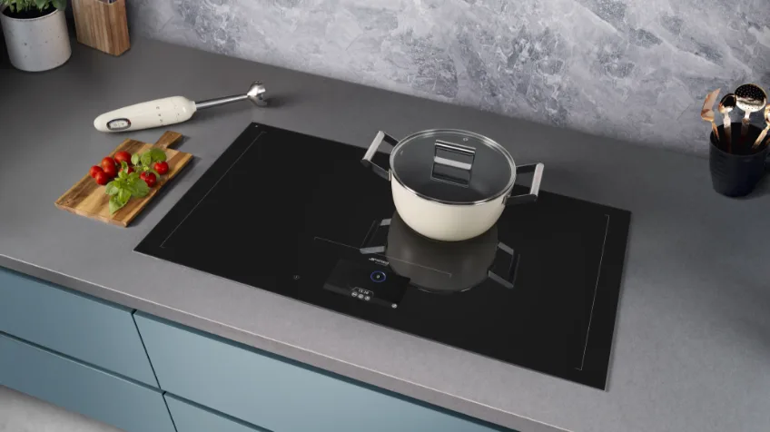 A Smeg induction cooktop in a grey kitchen with a white pot on top of it
