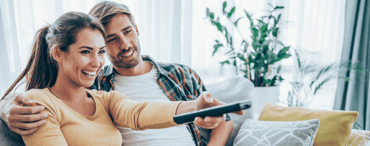 A young couple cuddle while watching TV at home