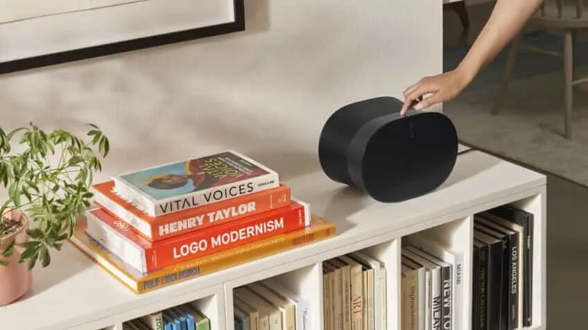 Woman adjusting the sound at the top of her black Sonos Era 300 in trendy living room 