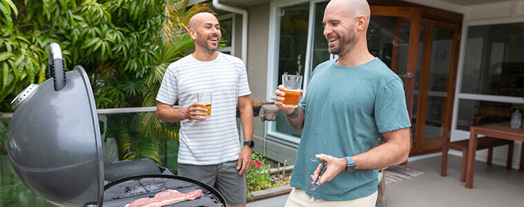 Two men barbeque together outside