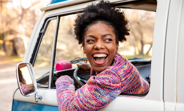 A woman listens to music with a portable speaker in the car as she drives
