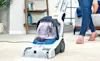 A woman cleans her living room carpet with the Vax Compact Power Carpet Cleaner