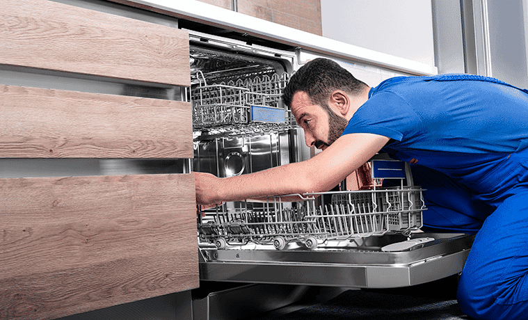 A delivery person finishes installing a new dishwasher