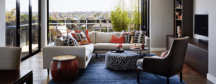 Modern lounge room with bright textiles and green views
