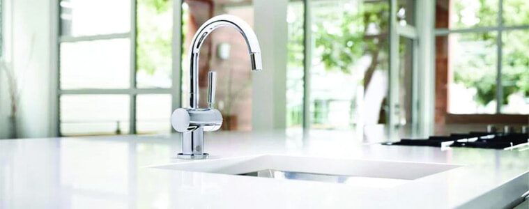 A silver gooseneck mixer tap in a white kitchen