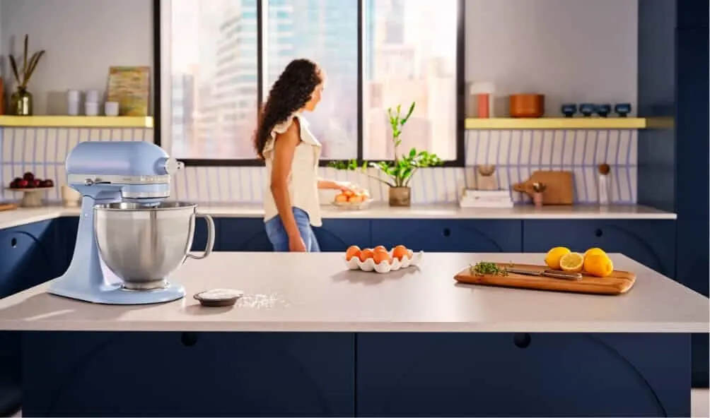 Woman walking around her kitchen with her COTY KicthenAid Stand Mixer in vibrant Salt Blue