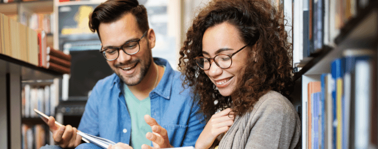 A young male student enjoys a coffee break while checking his smartphone