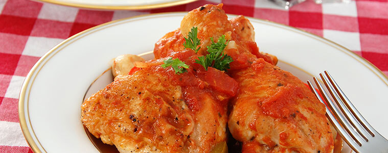 Overhead shot of chicken cacciatore in white casserole dish