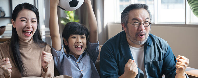 family sitting on the coach watching football together on the TV