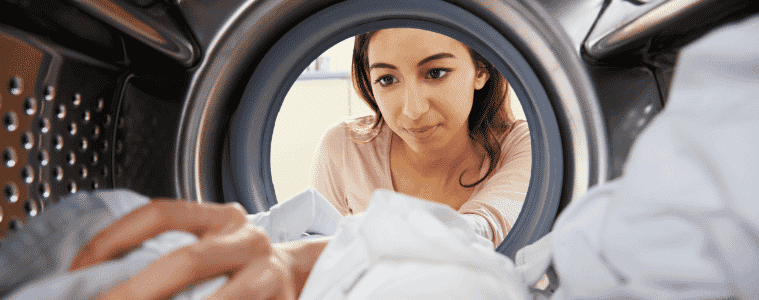 A woman reaches inside her dryer to remove some freshly dried clothes