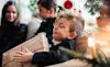 Smiling boy holding a Christmas present while sitting with family