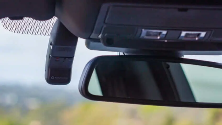 A Navman dash cam is attached to the windscreen of a car