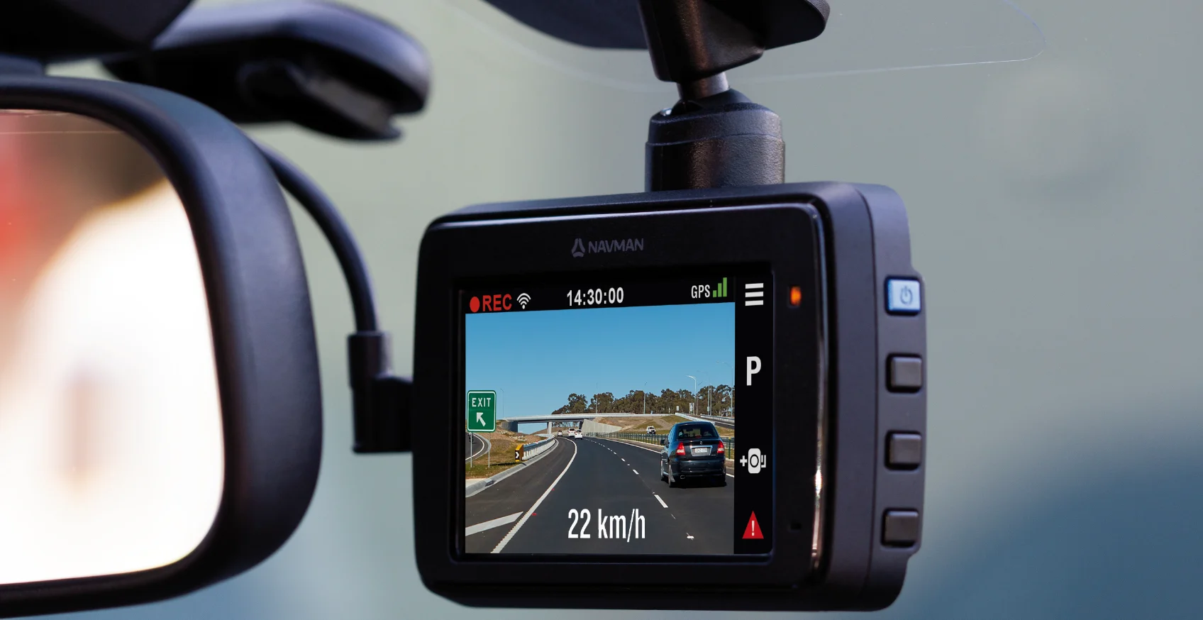 A Navman dash cam is attached to the windscreen of a car