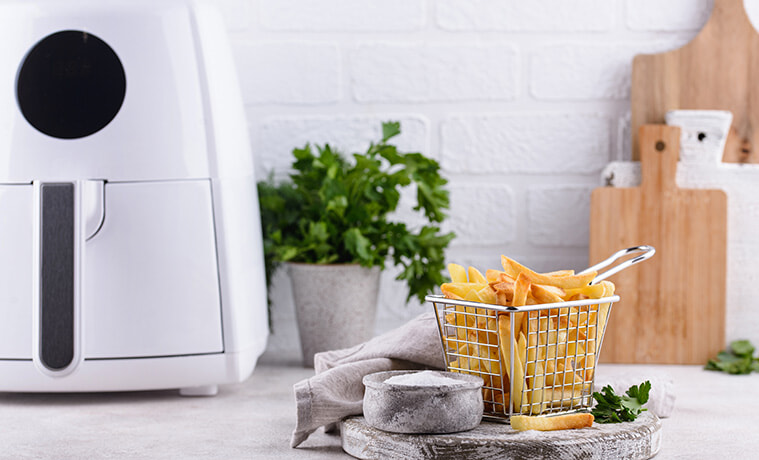 French fries near an air fryer on a kitchen bench