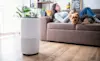 Woman using a digital tablet to set up a home air purifier in her living room