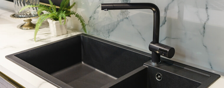 A black sink and tap in a white kitchen