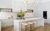 White coastalstyle kitchen with marblelook island and herringbone floors