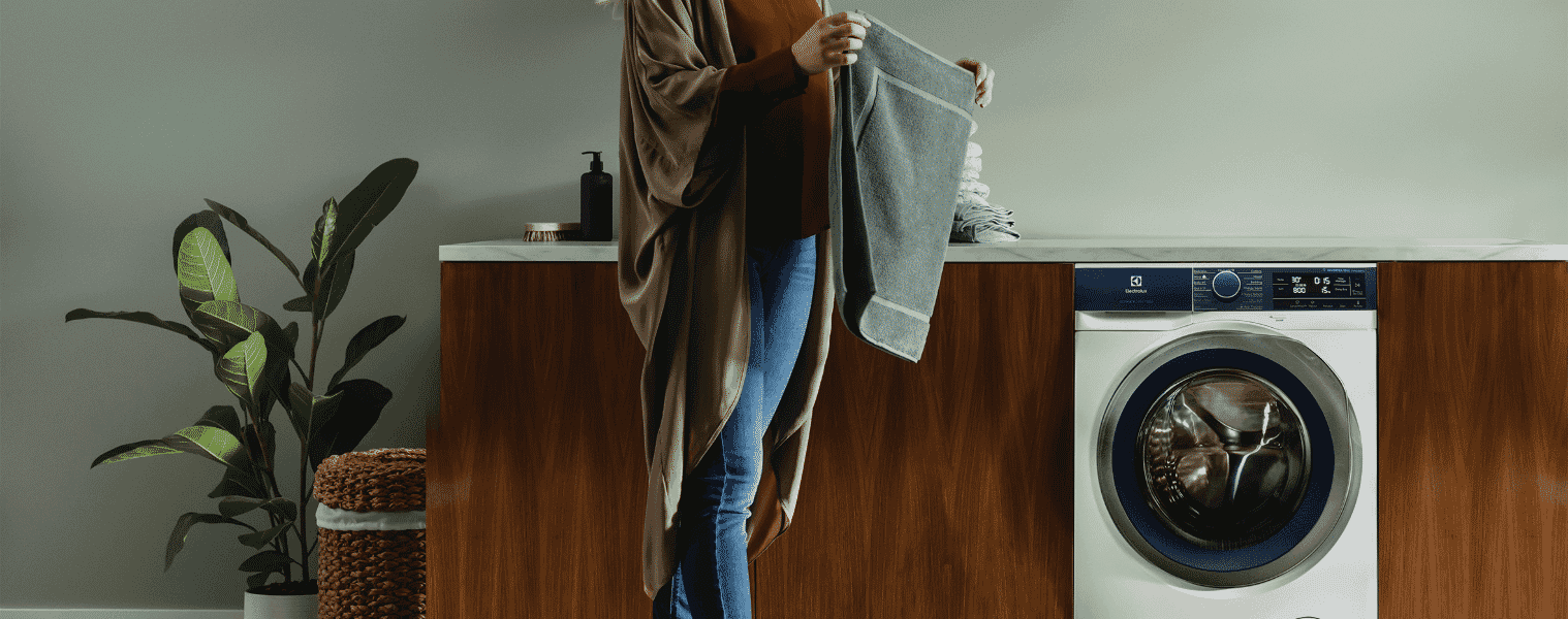 A woman folds her laundry in her laundry room