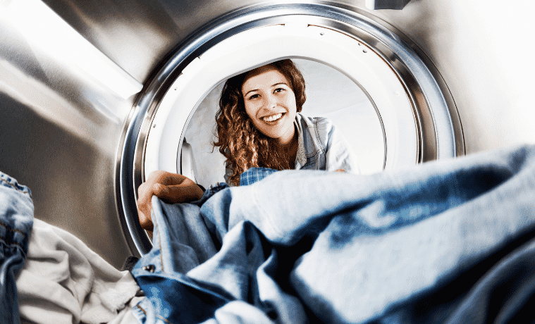 Internal view of a dryer as a woman unloads her clothes