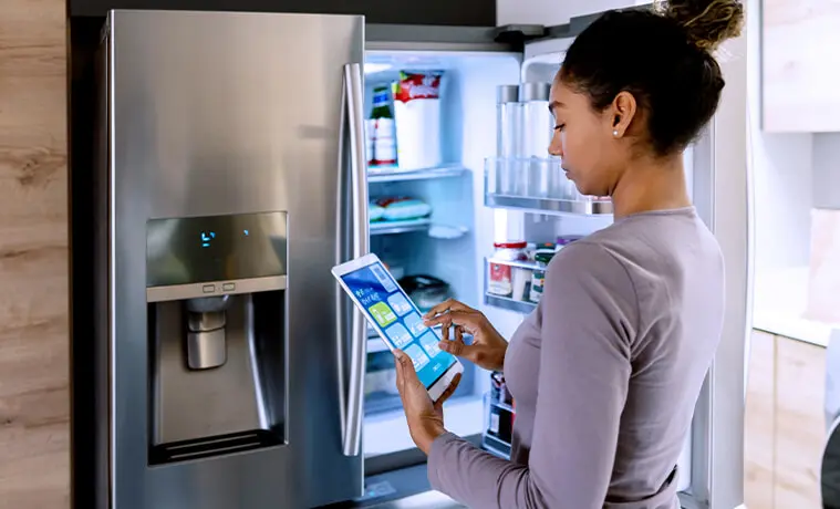 Woman controlling her smart fridge using an app on a tablet