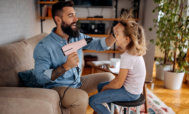 A woman dries her long hair using a hair dryer