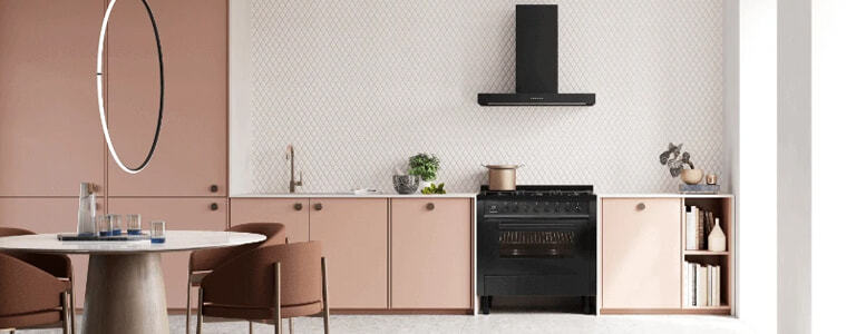 A stylish pink kitchen with a black freestanding oven