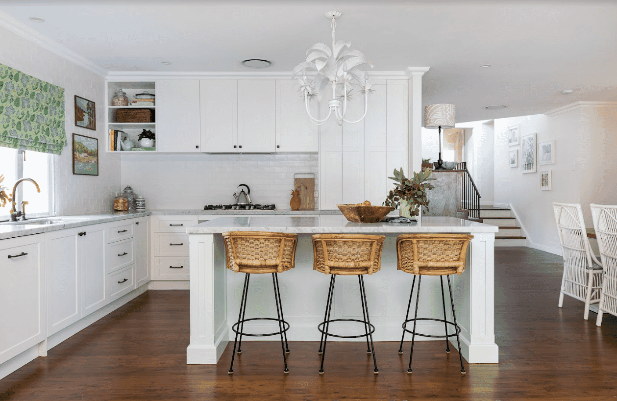 White Hamptonsstyle kitchen with cane breakfast stools