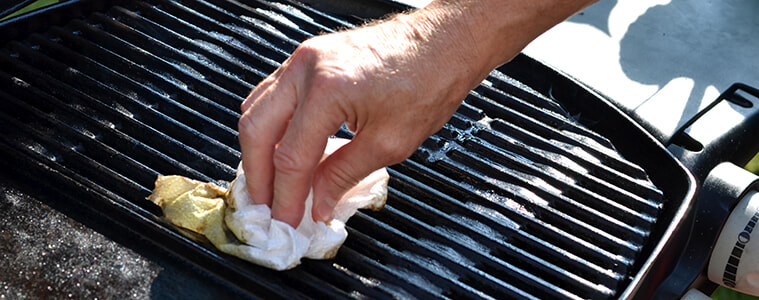 A man uses a brush to clean his barbecue grill plate 