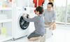 A father shows his son how to use the front loader washing machine in their laundry at home