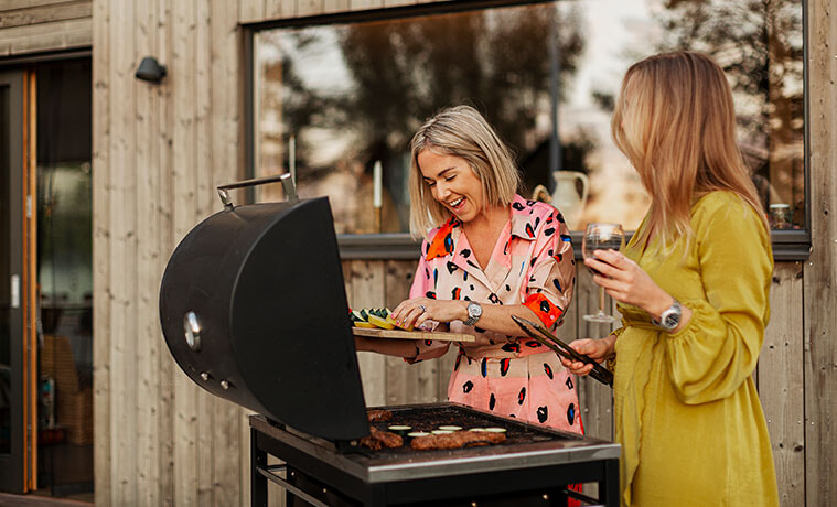 Smiling female friends prepare food on a barbecue