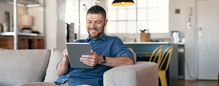 a man sitting on his couch on his iPad 